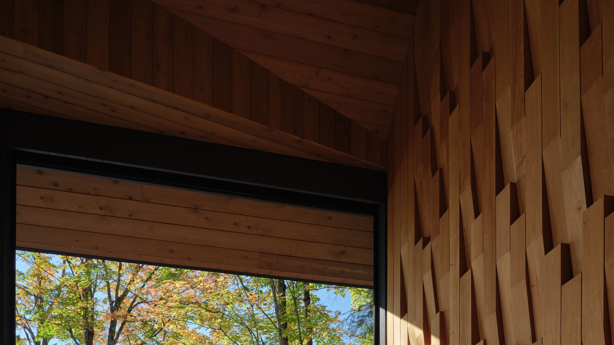 halboffene Veranda mit strukturierter Zedernholzwand Sessel Sofa Seeblick