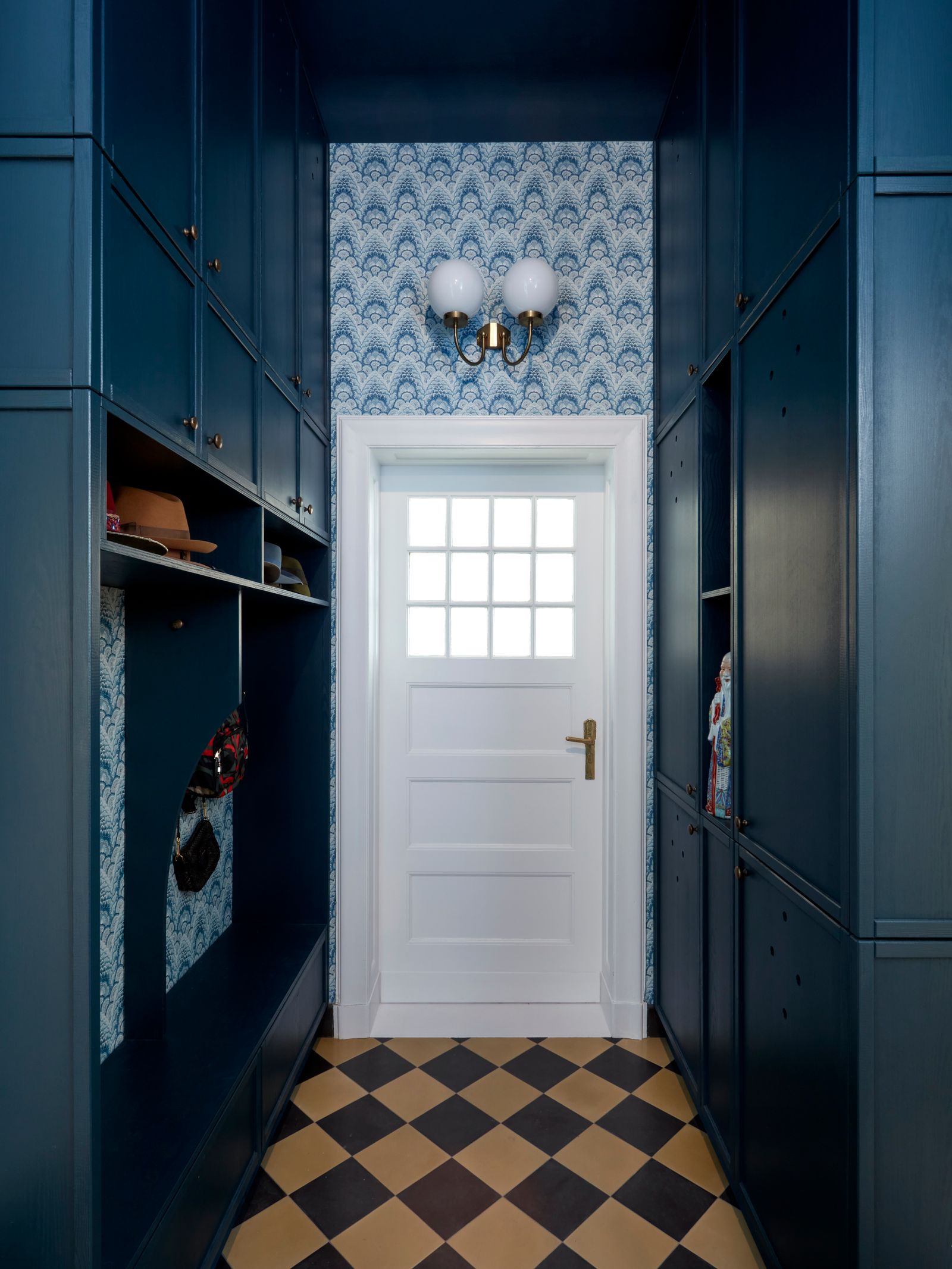 Der dunkelblaue Flur mit gemusterter Tapete und karierten Fliesen.