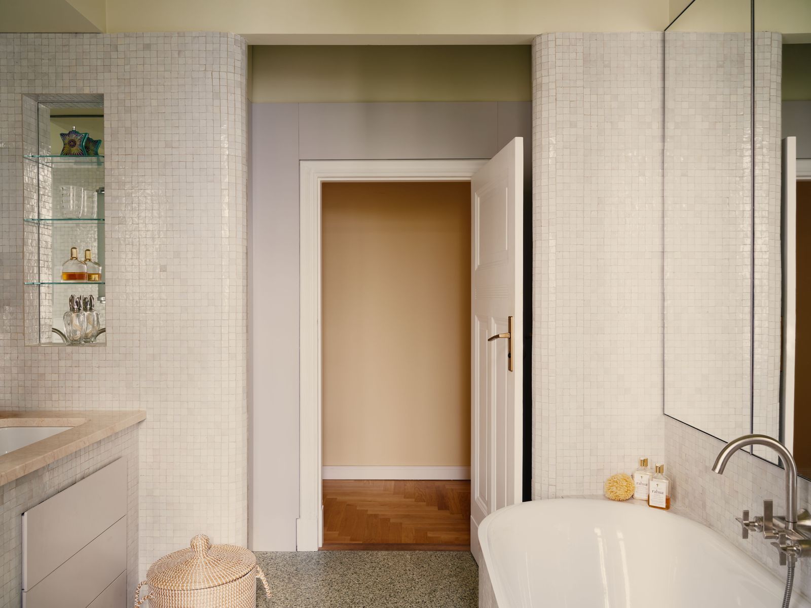 Im Bad wurde ein TerrazzoBoden verlegt. Die Wände sind mit hellgrauem Mosaik verfließt.