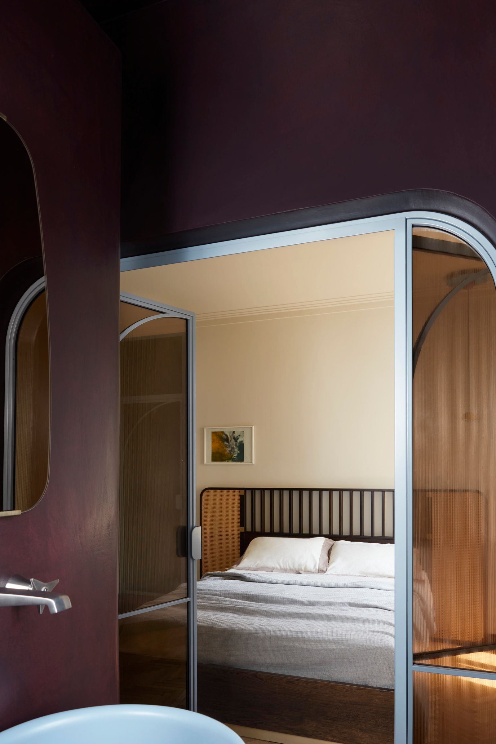 Blick aus einem bordeauxroten Bad ins Schlafzimmer