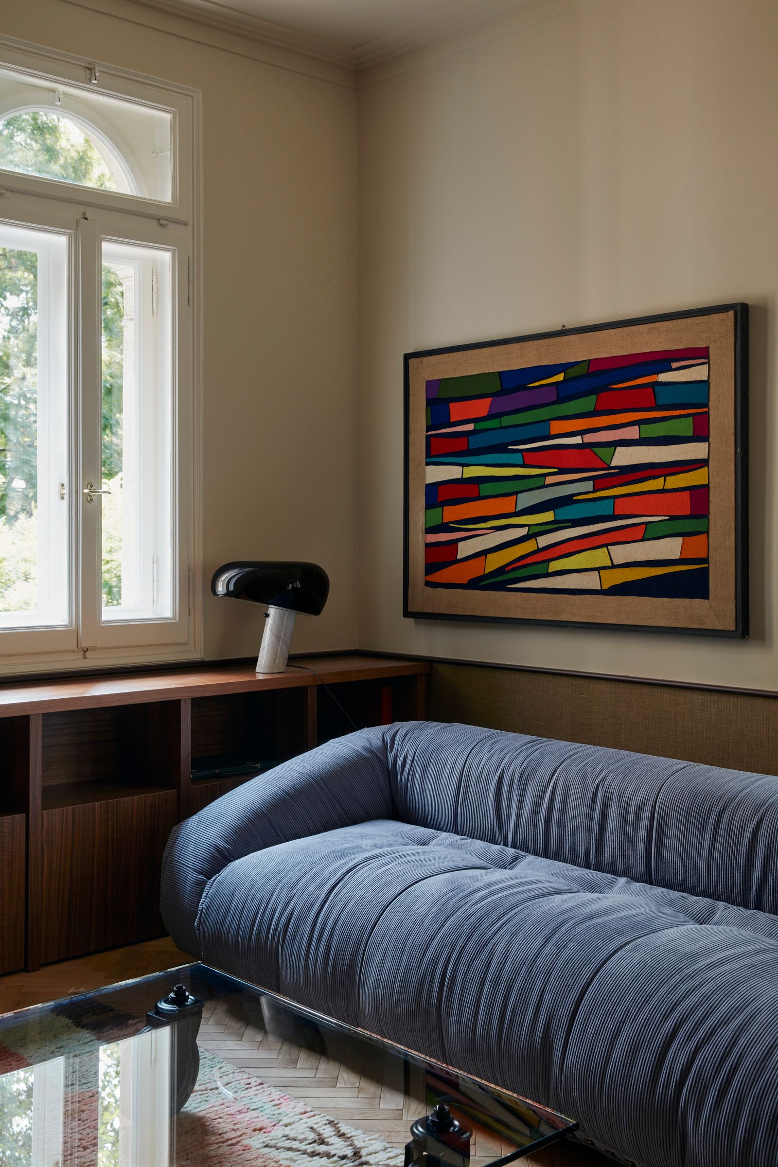 Wohnzimmer mit blauem Sofa und abstraktem buntem Gemälde