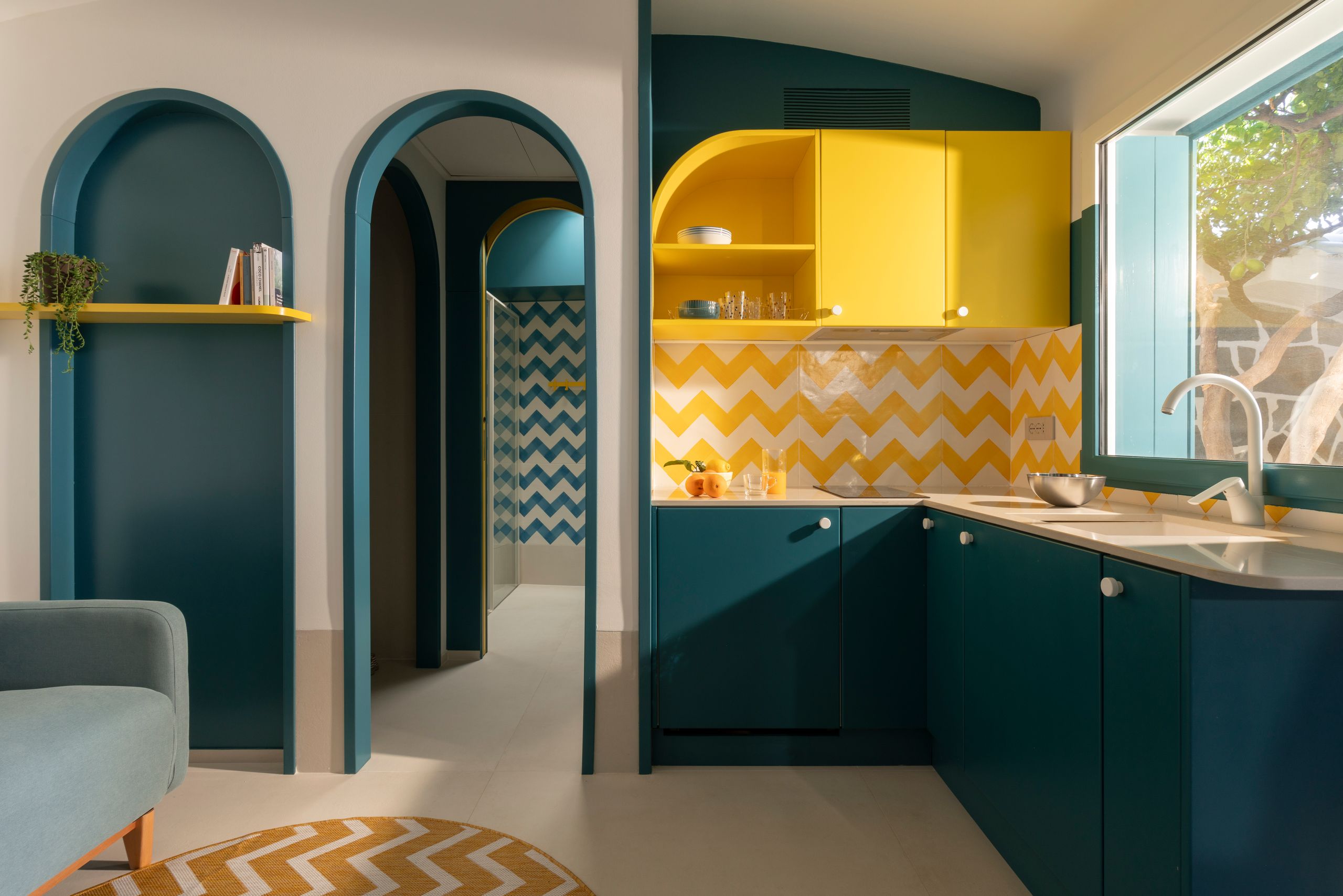 Petrolblaue Küchenzeile gelbe Oberschränke Spritzschutz aus gelbweißen Fliesen